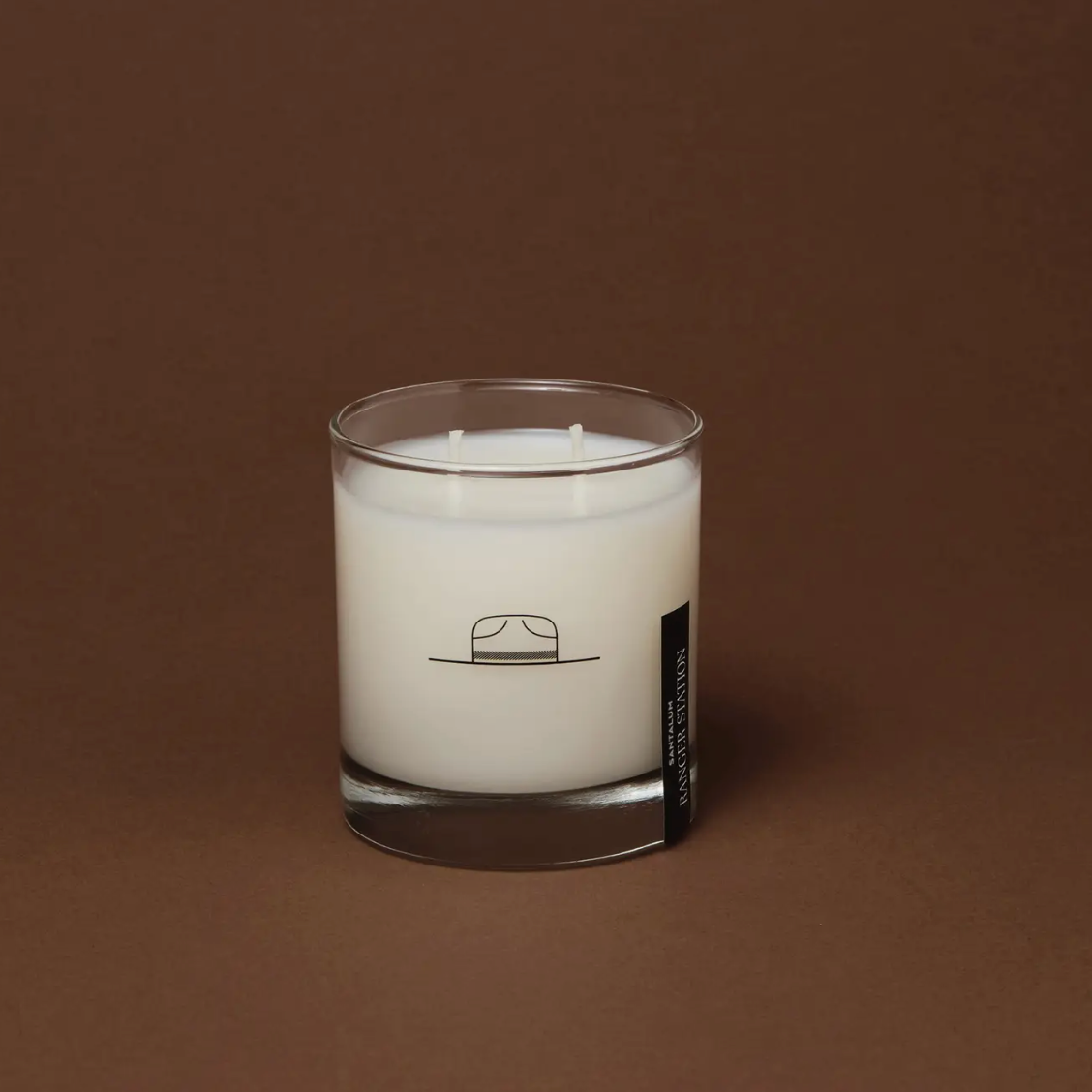 Santalum candle in a glass container with a label on a brown background